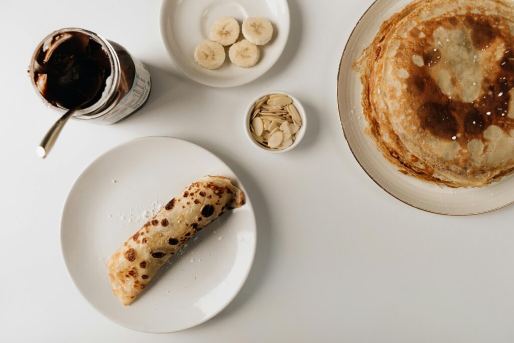 A delightful breakfast setup featuring pancakes with banana slices and chocolate spread.